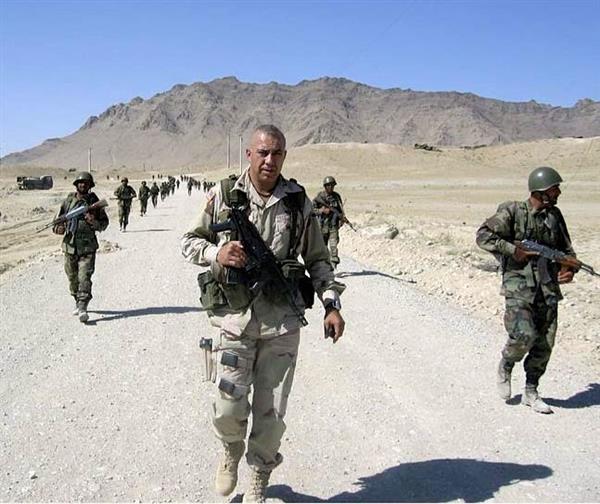 Col. Tom Brewer and other soldiers walk down a gravel road